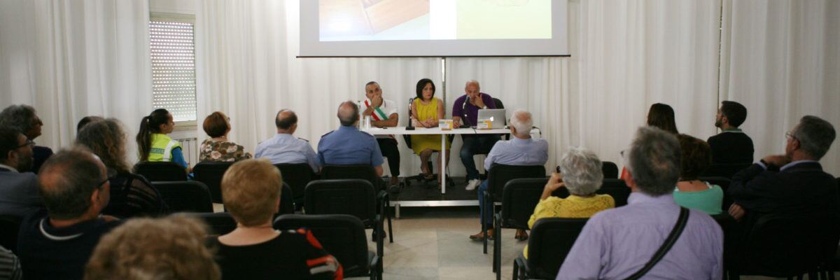 Conferenza pubblica al KISS con relatori al tavolo e pubblico seduto