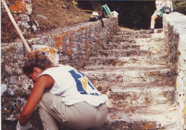 Volontaria al lavoro sulla scalinata in pietra del Sentiero Punico di Erice